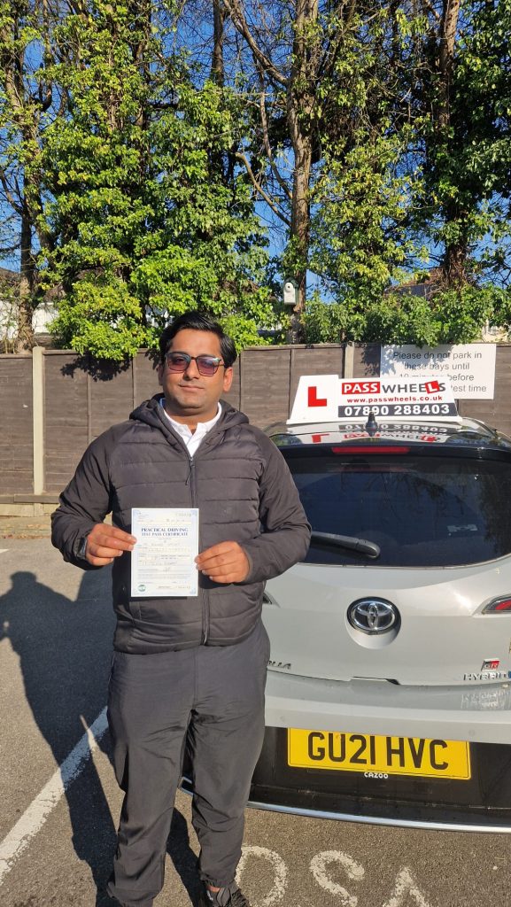 Pass Wheels pupil holding their practical driving test pass certificate beside the school car