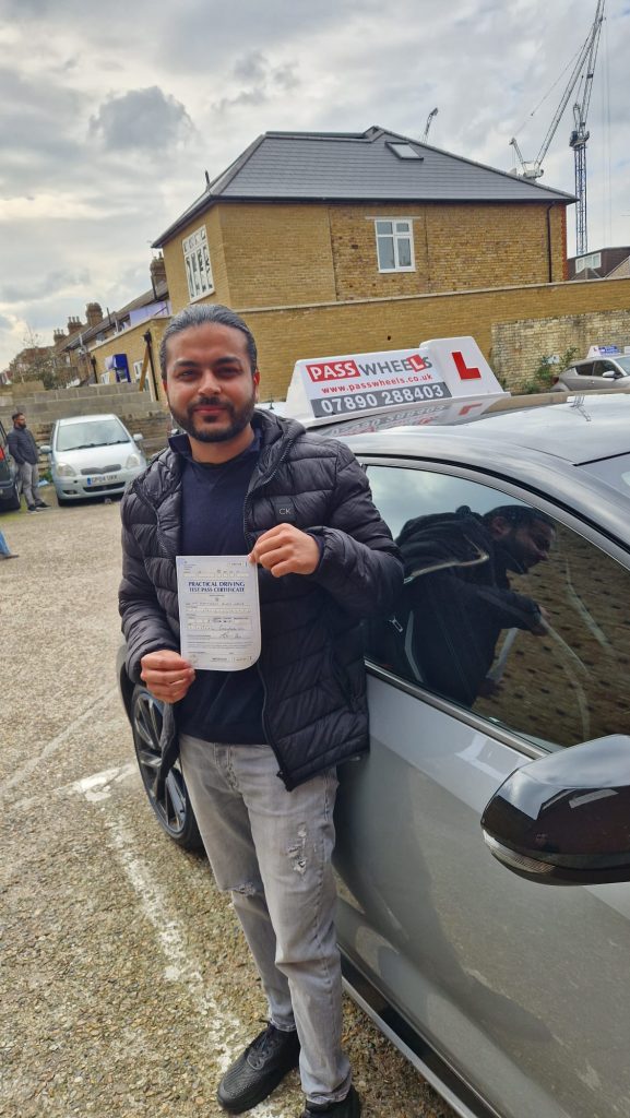 Pass Wheels pupil holding their practical driving test pass certificate beside the school car
