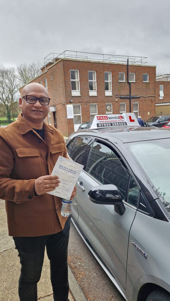 Pass Wheels pupil holding their practical driving test pass certificate beside the school car
