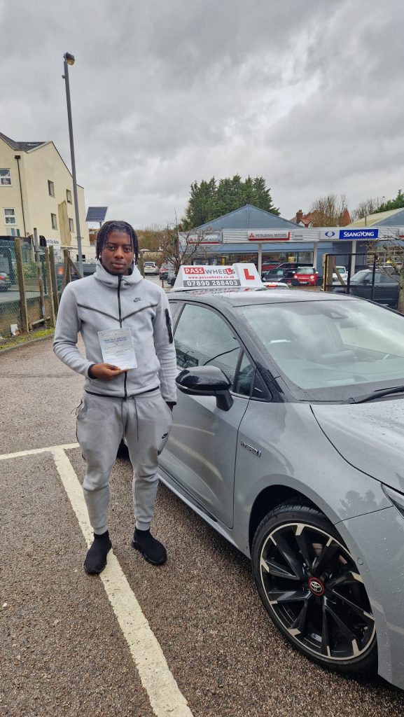 Pass Wheels pupil holding their practical driving test pass certificate beside the school car