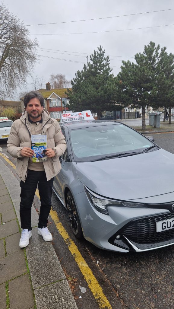 Pass Wheels pupil holding their practical driving test pass certificate beside the school car